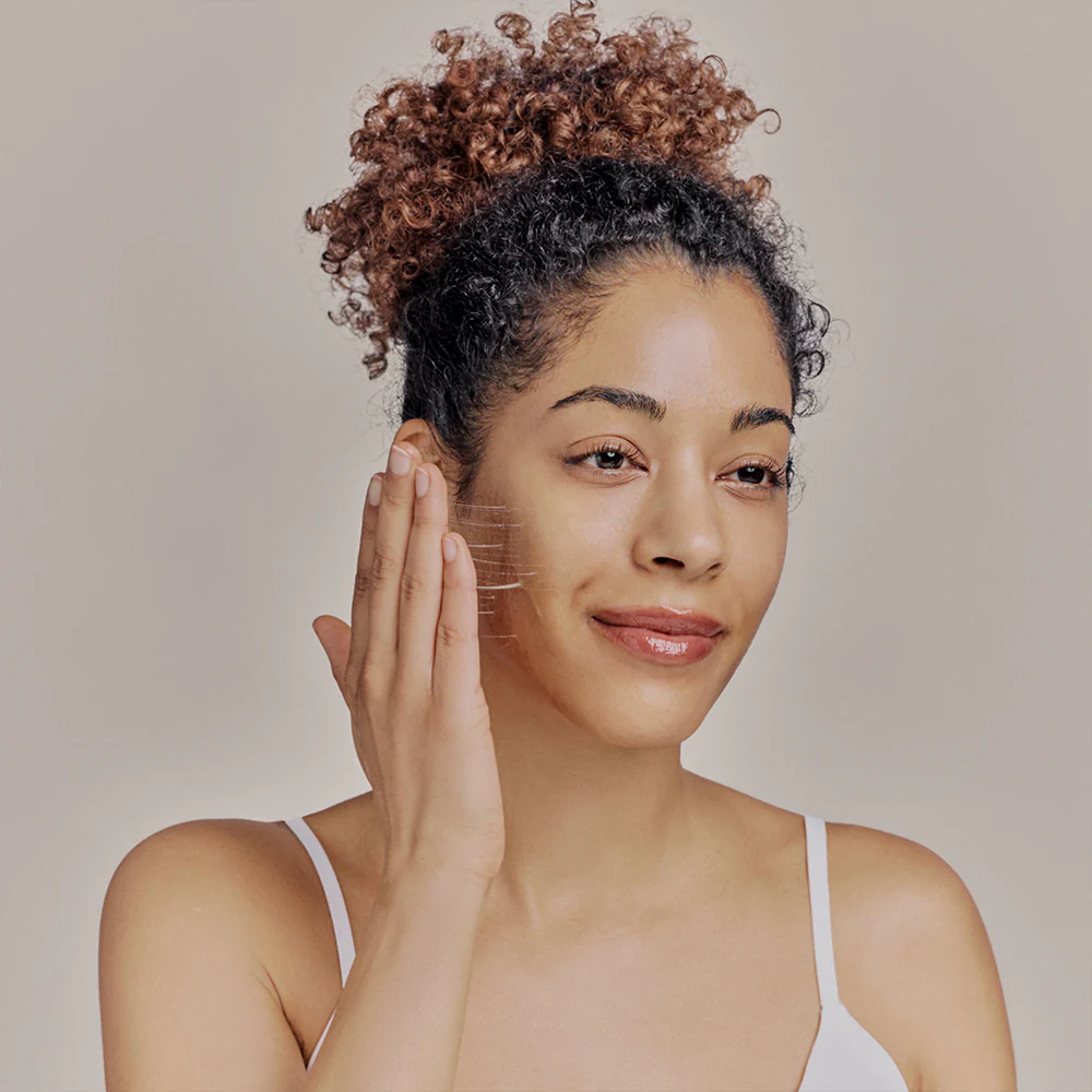 Whamisa Woman applying skincare product to face, promoting healthy glowing skin | Available at budcosmetics.com